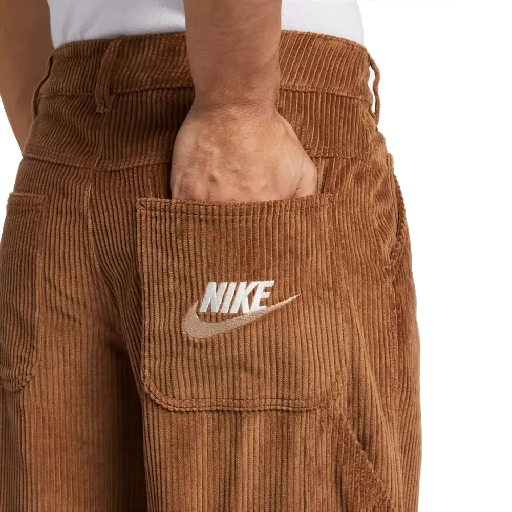 Крупный план кармана: коричневый вельвет с вышивкой Nike. Детали карманов подчеркивают функциональный и модный дизайн