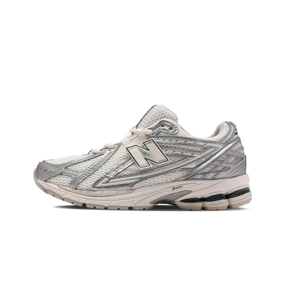 Серебристые кроссовки New Balance 1906R с металлическим блеском. Ракурс сбоку: текстурированная сетка, ретро-форма и белая подметка