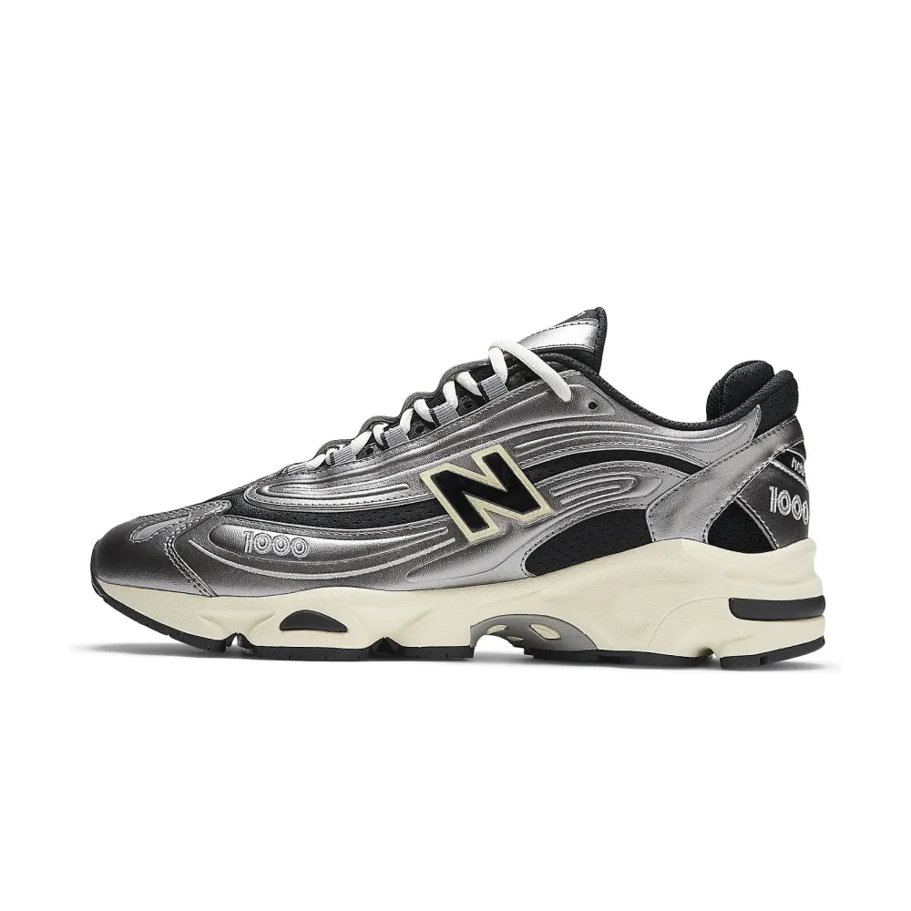 Серебристые кроссовки New Balance 1000, боковой ракурс. Металлический блеск и стильный дизайн с черными акцентами